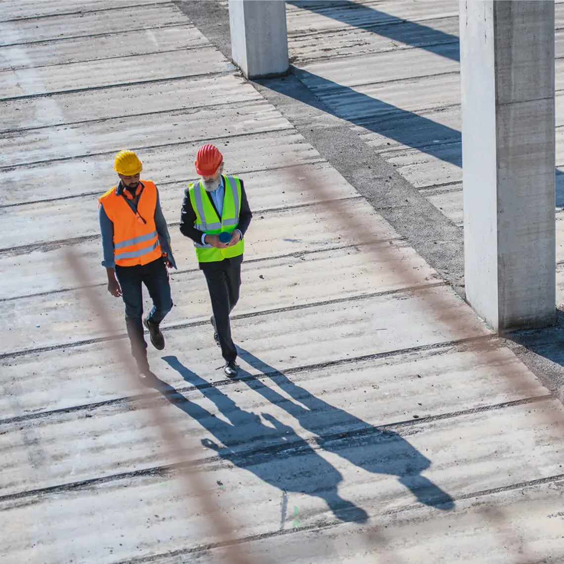 Construction workers walking on concrete slabs.