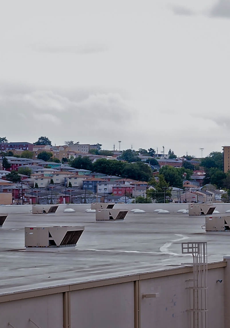 Rooftop with cityscape and cloudy sky.